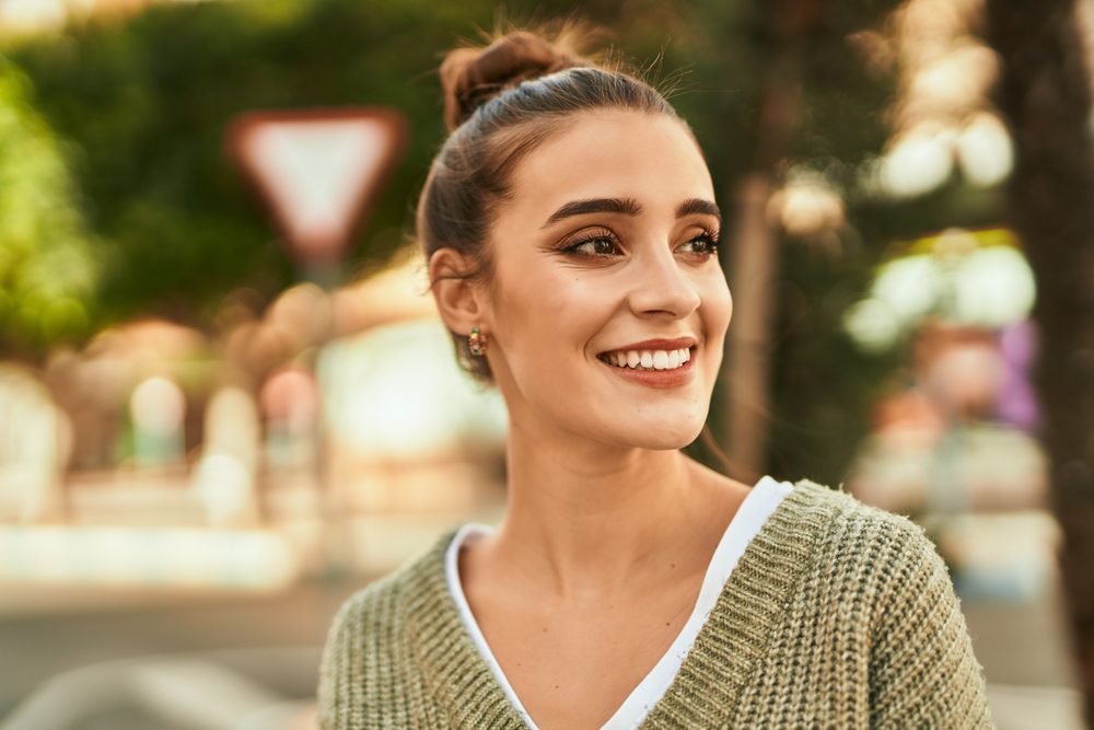 Young woman smiling outdoors showcasing bright healthy smile – Dentist in Tustin CA